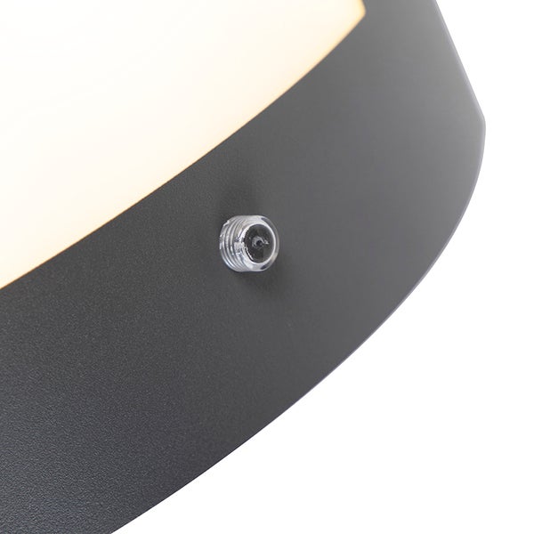 Nahaufnahme einer Leuchte mit dunklem Gehäuse, einer hellen Lichtaustrittsfläche und einem integrierten Sensor.