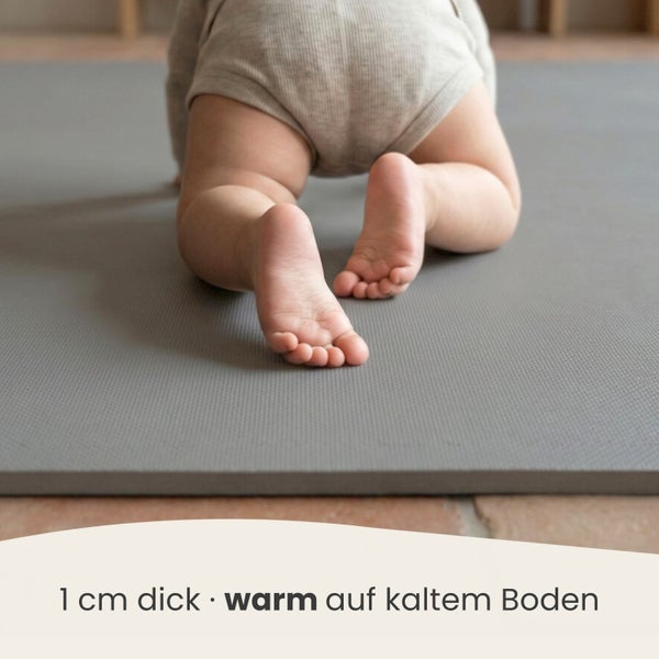 Ein Baby krabbelt auf einer 1 Zentimeter dicken grauen Spielmatte, die Wärme auf kaltem Boden bietet.