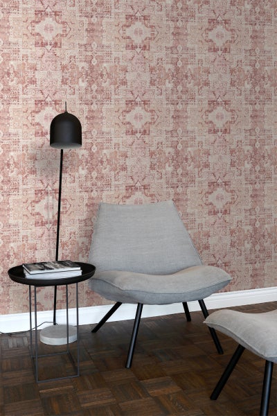 Szene mit gemusterter Tapete, Sessel, Fußhocker, Tisch und Lampe