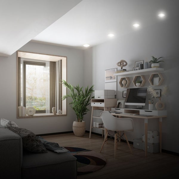 Heller, moderner Arbeitsplatz mit weißem Schreibtisch, Monitor, Bürostuhl, Pflanzen und vier runden LED-Einbauleuchten an der Decke.