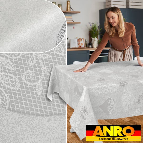 Hellgraue Tischdecke mit Herzen und Rosen in Spitzenoptik auf einem Tisch in einer modernen Küche, Detailansicht der Oberflächenstruktur, ANRO Logo.