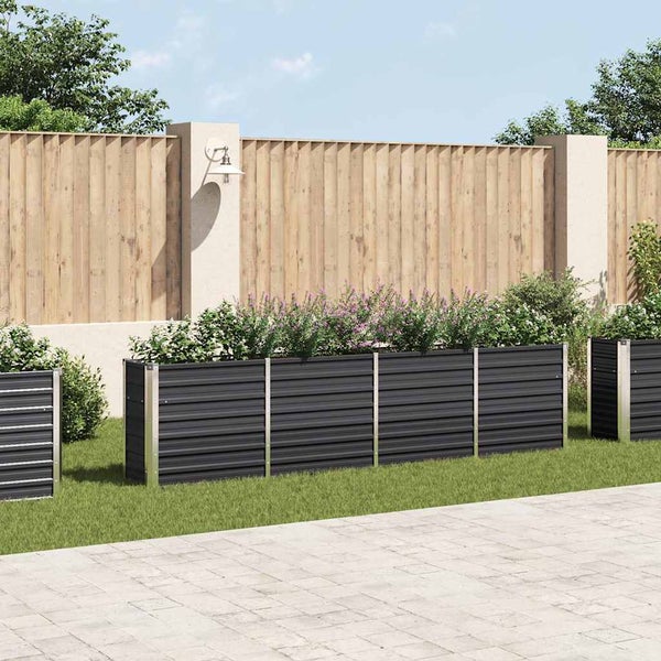 Modulares Hochbeet aus Metall in einem Garten vor einem Holzzaun mit Bepflanzung auf Rasenfläche.