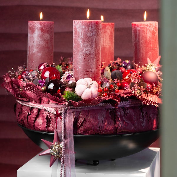 Adventskranz mit vier Kerzen, Kugeln und dekorativen Elementen in einer Schale.