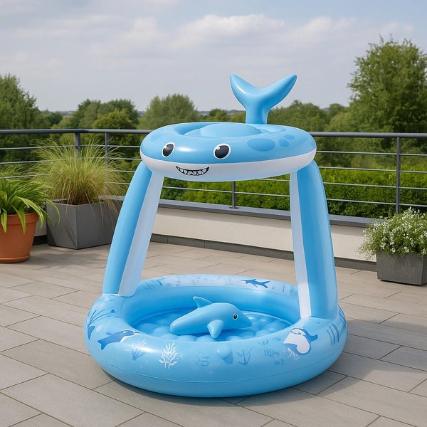 Aufblasbarer Kinderpool in Haifischform mit Sonnendach und kleinem Spielzeugfisch auf einer Terrasse.