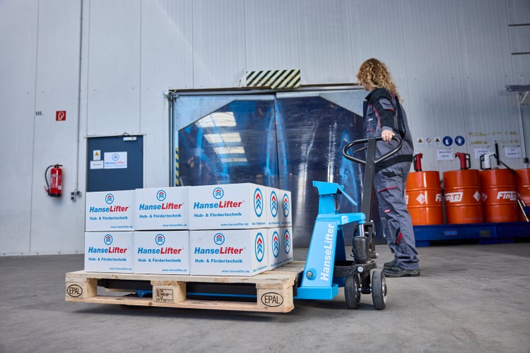 Eine Person in Arbeitskleidung bedient einen blauen HanseLifter Hubwagen mit beladener EPAL-Palette in einem hellen, organisierten Lager.