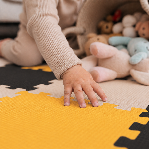 Kind spielt auf einer Puzzlematte aus Schaumstoff mit Spielzeug in einem Kinderzimmer