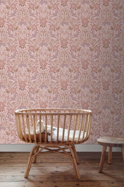Kinderzimmer mit ornamental gemusterter Tapete mit Blumen und Vögeln, einem Babybett aus Rattan und einem Holzhocker auf Dielenboden.