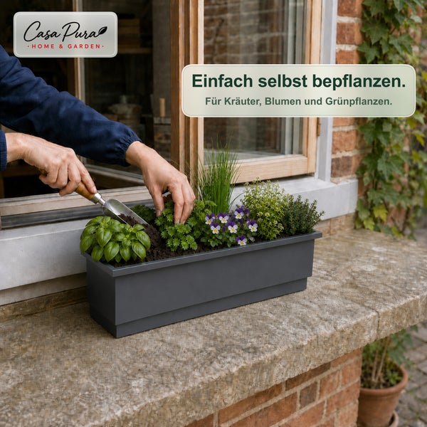 Person bepflanzt rechteckigen Blumenkasten auf einer Fensterbank mit Kräutern und Blumen mithilfe einer kleinen Gartenschaufel.
