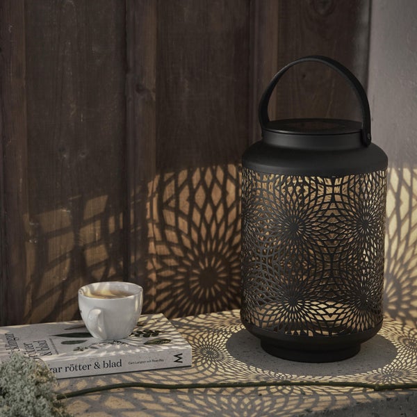 Dekorative Laterne mit Muster, Buch und Tasse