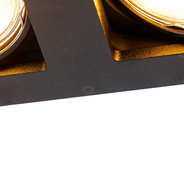 Detailansicht einer schwarzen Leuchte mit goldfarbener Innenseite und zwei runden Leuchtmitteln.