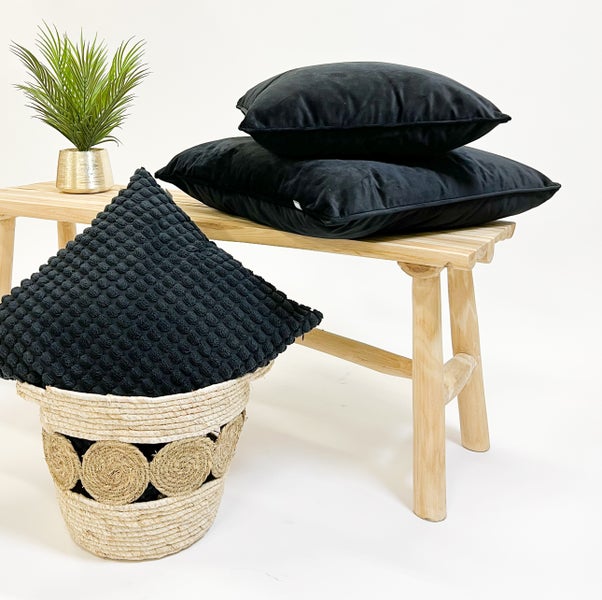 Dekorative Szene mit schwarzen Kissen, Bank und Korb