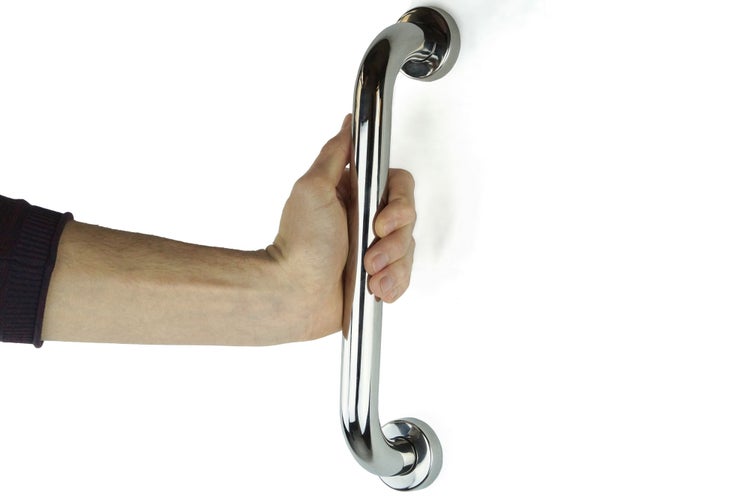 Wandmontierter Haltegriff aus verchromtem Metall, gehalten von einer Hand zur Demonstration der Sicherheit im Bad.