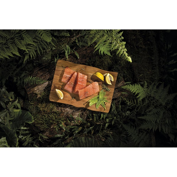 Lachsfilet auf Holzbrett mit Zitrone und Erbsen in natürlicher Umgebung
