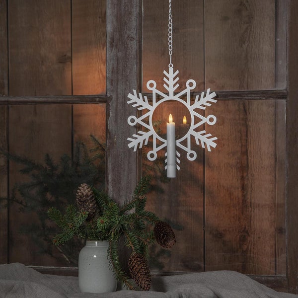 Dekorative Schneeflocke mit Kerze an einer Kette vor einem Fenster