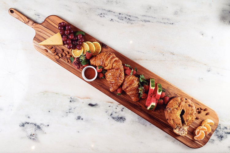 Holzschneidebrett mit Käse, Trauben, Mandeln, Orangen, Granatapfel, Marmeladentöpfchen, Croissants, Erdbeeren, Wassermelone, Kuchen und Mandarinen