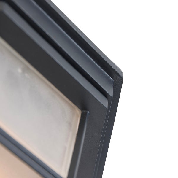 Nahaufnahme des Metallrahmens einer Außenleuchte in Dunkelgrau mit mattiertem Glaseinsatz.