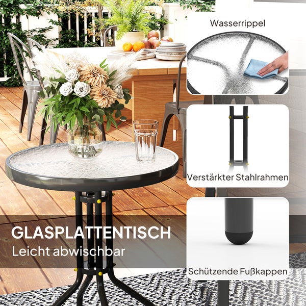 Runder Gartentisch mit strukturierter Glasplatte und schwarzem Stahlrahmen auf einer hellen Holzterrasse mit Blumen und Stühlen.