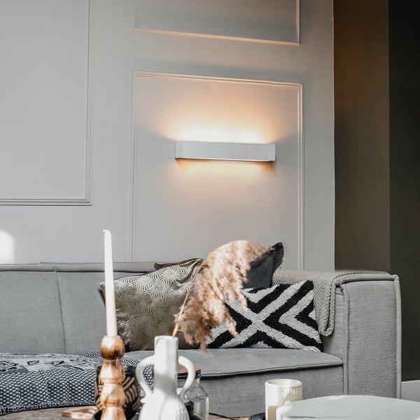 Wohnzimmer mit Couch und weißer Wandleuchte