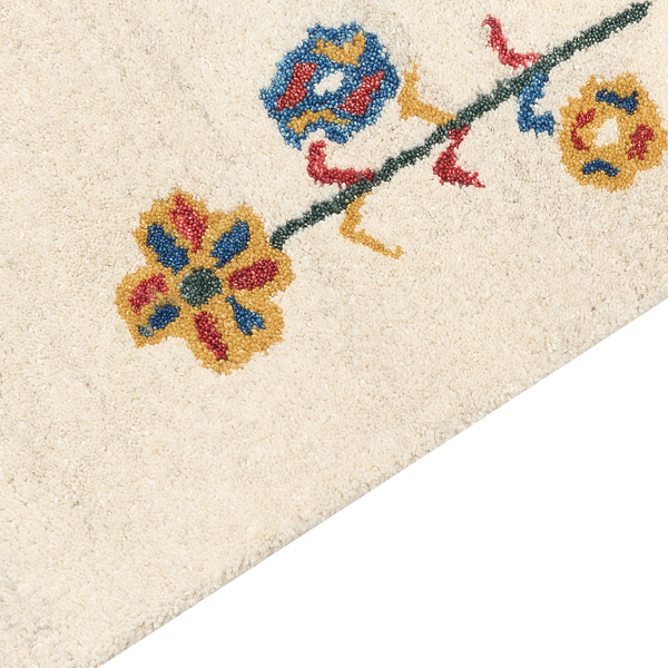 Detailansicht eines weichen Teppichs mit floralem Muster und bunten Blüten an einer Ranke.