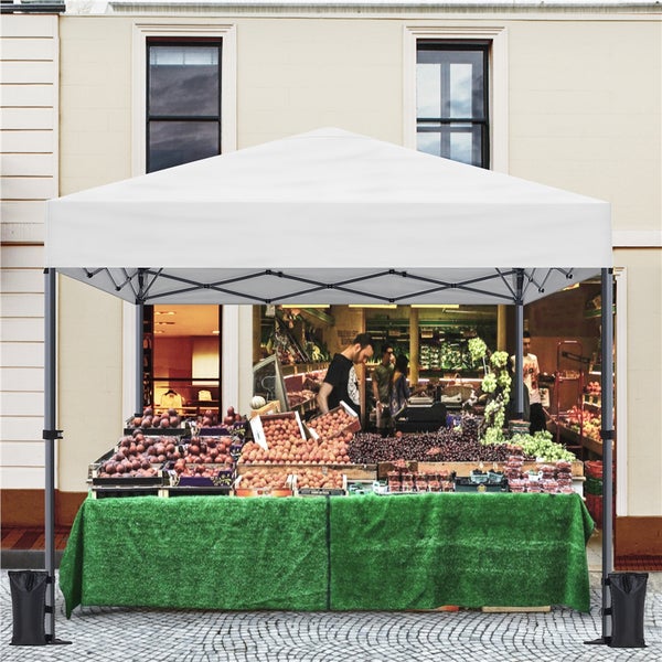 Verkaufsstand mit weißem Zeltdach, grauem Metallgestell, grünem Tisch und Sandsäcken zur Stabilisierung