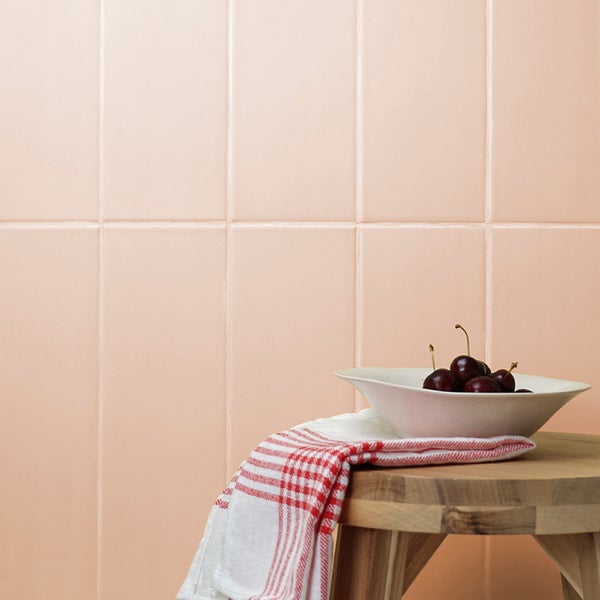 Wandfliesen im Rechteckformat verlegt an einer Wand mit einer Schale Kirschen auf einem Holzschemel.