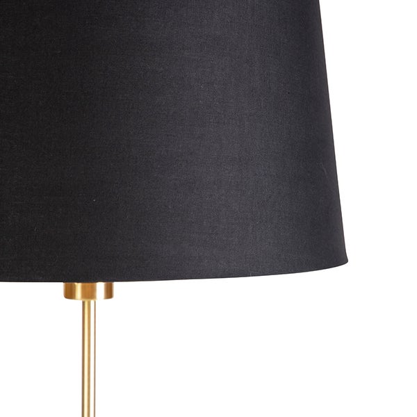 Nahaufnahme einer Lampe mit schwarzem Textilschirm und goldfarbenem Metallstativ.