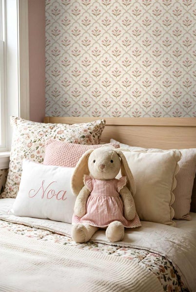 Helles Kinderzimmer mit floral gemusterter Tapete an der Wand und einem gemütlich hergerichteten Bett mit Kissen und Plüschhase.