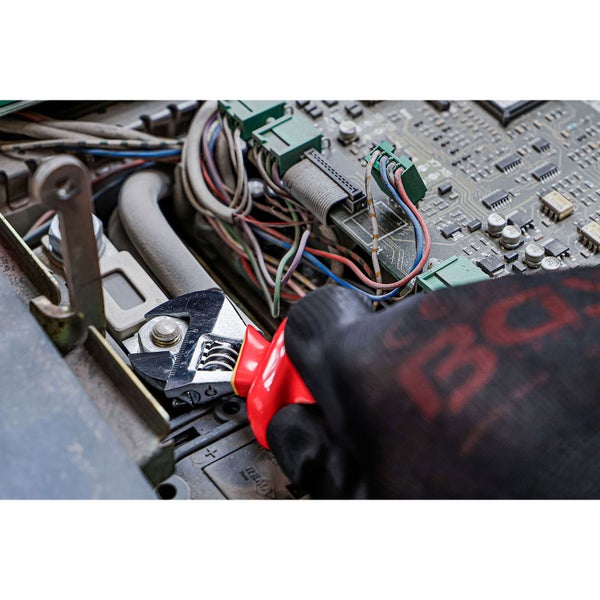 Ein verstellbarer Schraubenschlüssel wird für Reparaturen an einer Maschine mit Verkabelung und Leiterplatte verwendet.