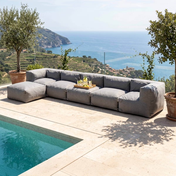 Modernes modulares Lounge-Sofa in Grau auf einer Steinterrasse am Pool mit Panoramablick auf das Meer.