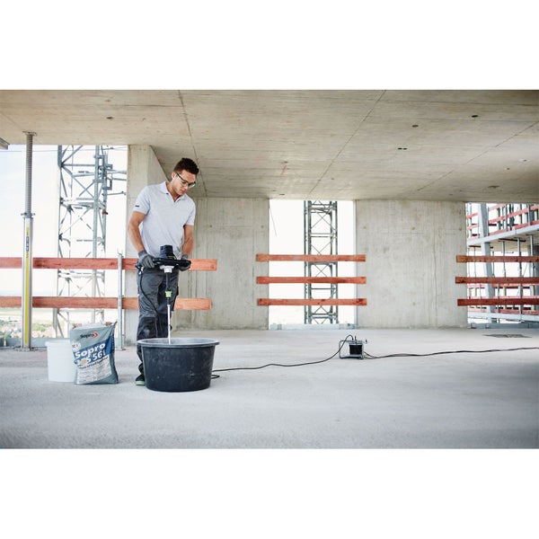 Handwerker rührt Sopro Anhydritfließspachtel mit einem elektrischen Rührwerk in einem Eimer auf einer Baustelle an.