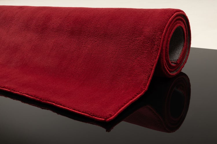 Roter, weicher Teppich mit kurzem Flor, einseitig aufgerollt.