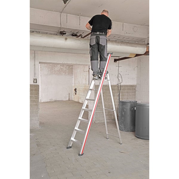 Mann steht auf einer Trittleiter und arbeitet in einem Raum.