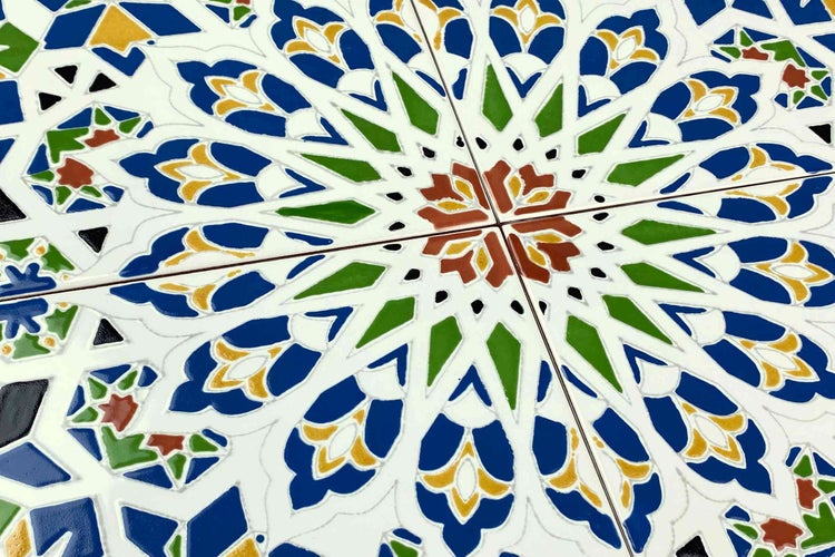 Küchenszene mit schwarzer Einbauküche, Arbeitsplatte aus Holz, Mosaikfliesen und verschiedenen Küchengeräten.