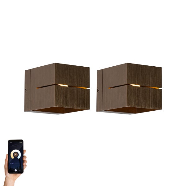 Zwei würfelförmige Wandleuchten mit einer Lichtlinie, die mit einem Smartphone gesteuert wird.