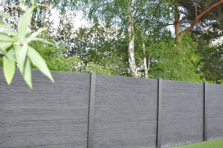 Grauer Sichtschutzzaun im Garten mit Bäumen im Hintergrund