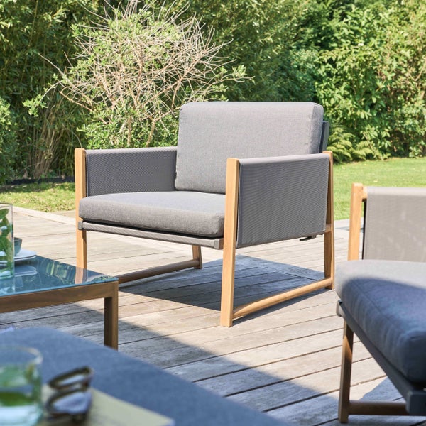 Moderner Gartencouchtisch mit Holzgestell und Glasplatte auf einer Holzterrasse mit Lounge-Möbeln.