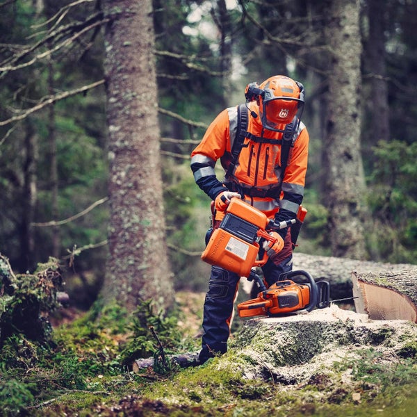 Forstarbeiter mit Schutzkleidung und Husqvarna Motorsäge im Wald.