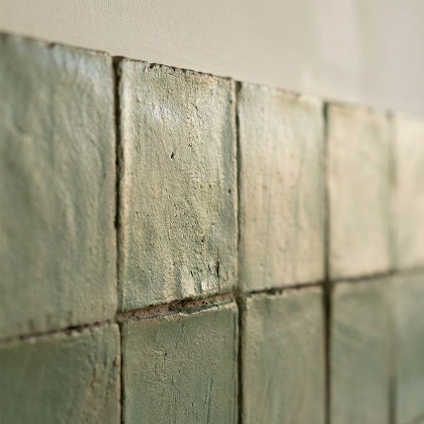 Quadratische Wandfliesen mit unebener strukturierter Oberfläche im Vintage Stil an einer Wand