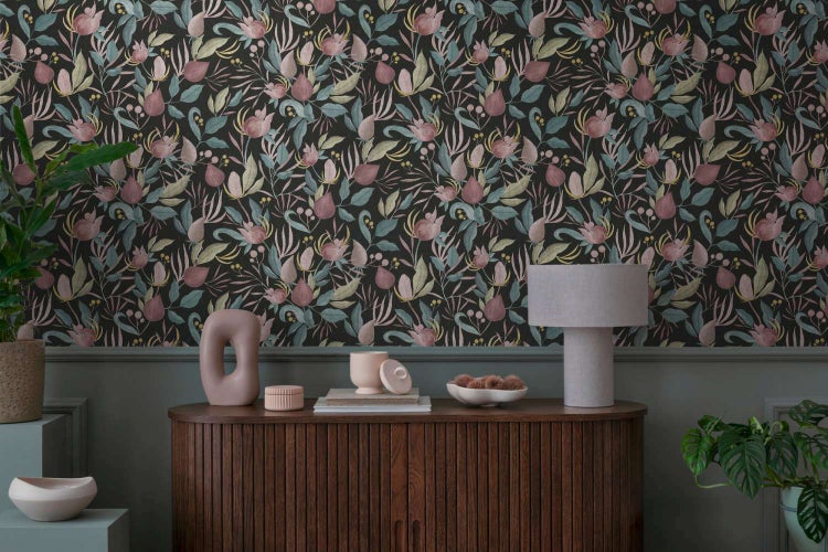 Wohnzimmer mit Vliestapete mit Blumenmuster vor einem Sideboard aus Holz mit Dekorationsgegenständen und Pflanzen.