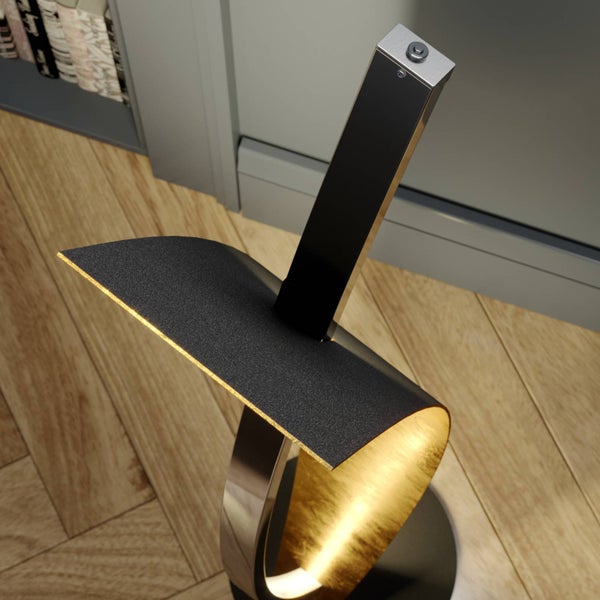 Moderne Stehleuchte mit gebogenem Schirm, außen schwarz strukturiert und innen goldfarben, auf einem Holzboden.