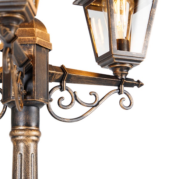 Detailansicht einer traditionellen Mastleuchte für den Außenbereich mit antikem Finish und verzierten Schnörkeln.