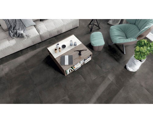 Dunkle quadratische Bodenfliesen in Betonoptik in einem modern eingerichteten Wohnzimmer mit Couchtisch und Sessel.
