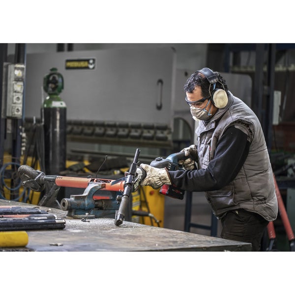 Ein Mann mit Schutzbrille, Mundschutz und Gehörschutz arbeitet mit einer Rohrkappenschere an einem Werkstück, das in einem Schraubstock eingespannt ist.