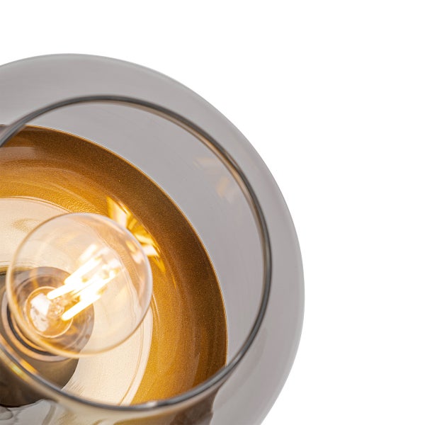 Detailansicht einer kugelförmigen Rauchglasleuchte mit goldfarbener Innenseite und eingeschaltetem LED-Leuchtmittel.
