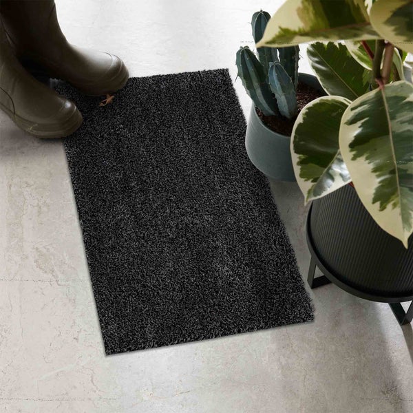 Schmutzfangmatte aus Textil neben Gummistiefeln und Pflanzen