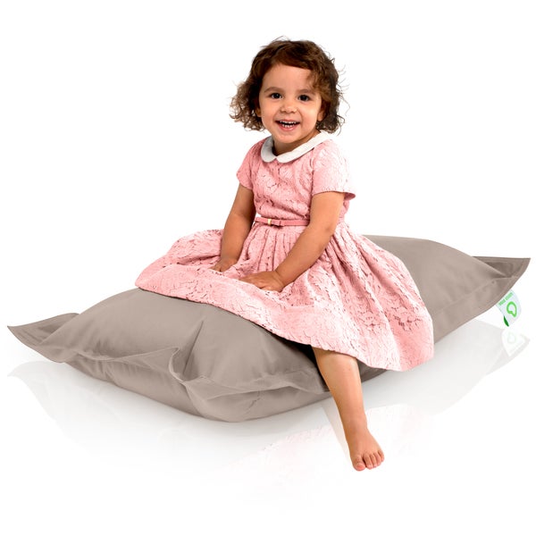Mädchen im Kleid sitzt auf großem Kissen
