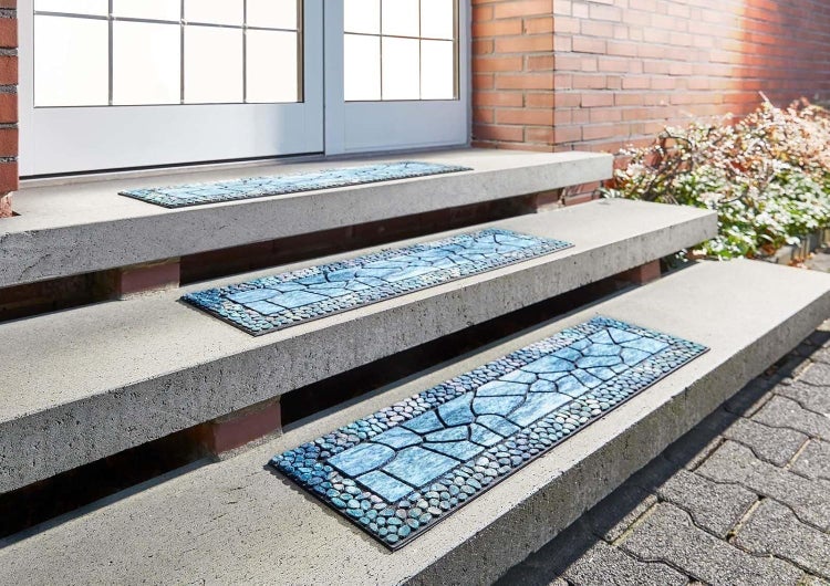 Stufenmatten mit Stein-Mosaik-Muster auf einer Betontreppe im Außenbereich.