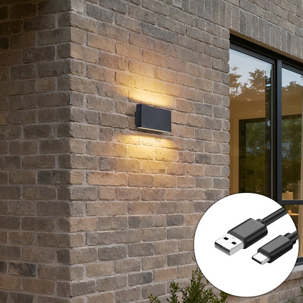 Moderne Außenwandleuchte an einer Ziegelwand mit Up-and-Down-Lichteffekt inklusive USB-Ladekabel in der Detailansicht.