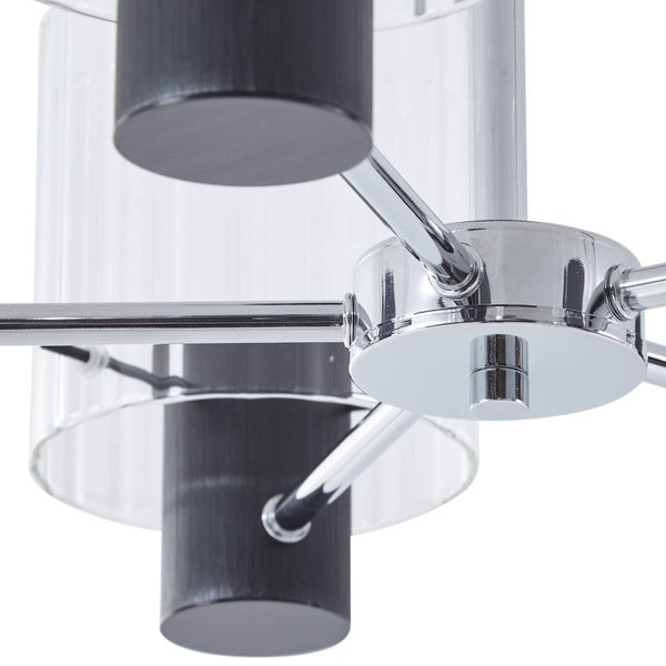 Detailaufnahme einer modernen Deckenleuchte mit verchromtem Metallgestell, schwarzen zylindrischen Elementen und geriffeltem Klarglas.