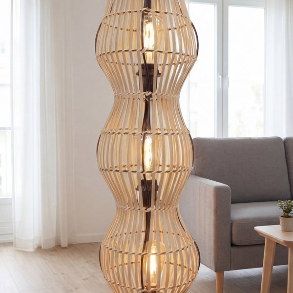 Dreistöckige Stehleuchte aus Bambusstreben in einem hellen Wohnzimmer neben einem grauen Sofa und einem Holztisch.